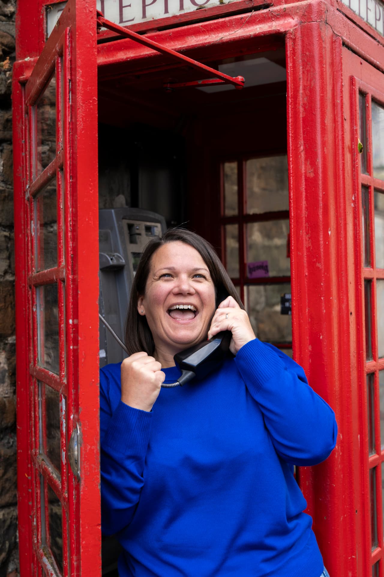 Leisa Pickles laughing on a handset inside a classic red phone box
